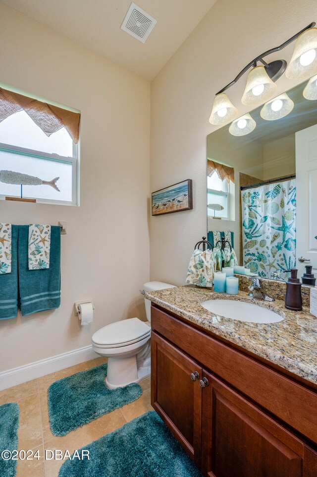 bathroom with vanity, plenty of natural light, tile patterned floors, and toilet