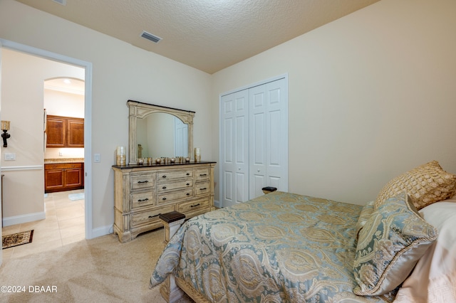 carpeted bedroom with a textured ceiling and a closet