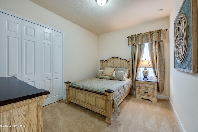 bedroom with a textured ceiling, light carpet, and a closet