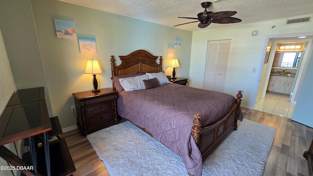 bedroom featuring a textured ceiling, visible vents, a closet, and light wood-type flooring