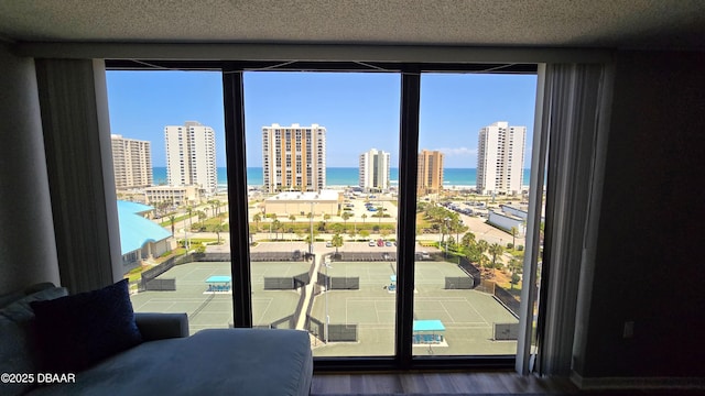 doorway to outside with a view of city, wood finished floors, a water view, and floor to ceiling windows