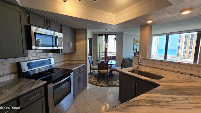 kitchen featuring light tile patterned floors, appliances with stainless steel finishes, ornamental molding, backsplash, and a sink
