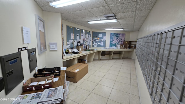 interior space with tile patterned flooring, a drop ceiling, and mail area