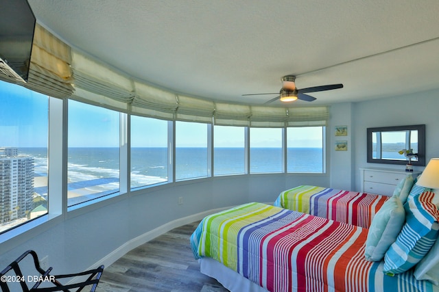 bedroom featuring hardwood / wood-style flooring, ceiling fan, and a water view