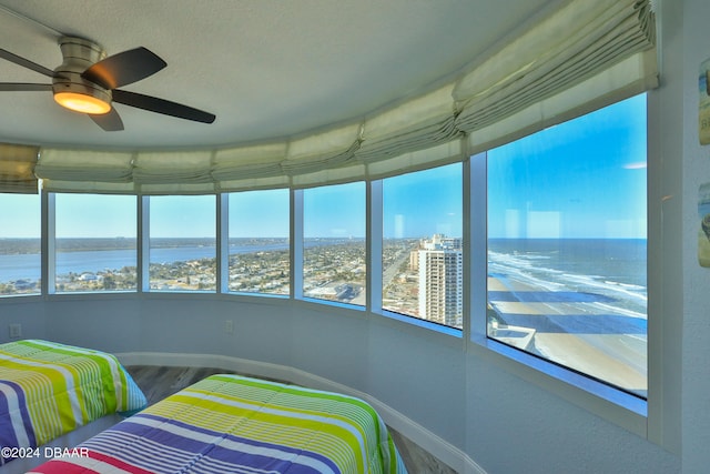 bedroom featuring hardwood / wood-style floors, ceiling fan, and a water view