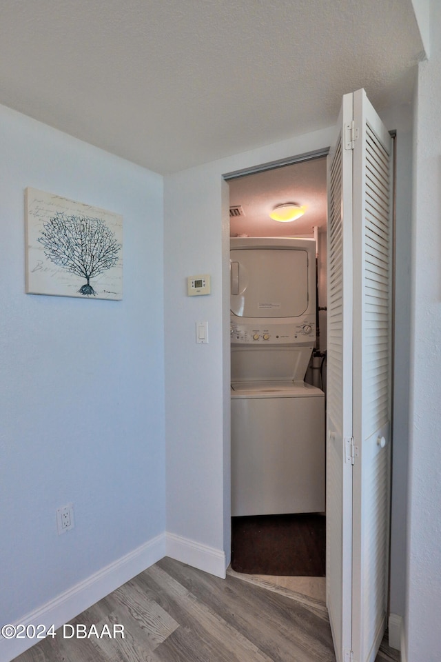 washroom featuring wood-type flooring and stacked washer / drying machine