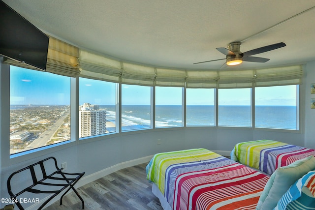 bedroom featuring a water view, multiple windows, ceiling fan, and wood-type flooring