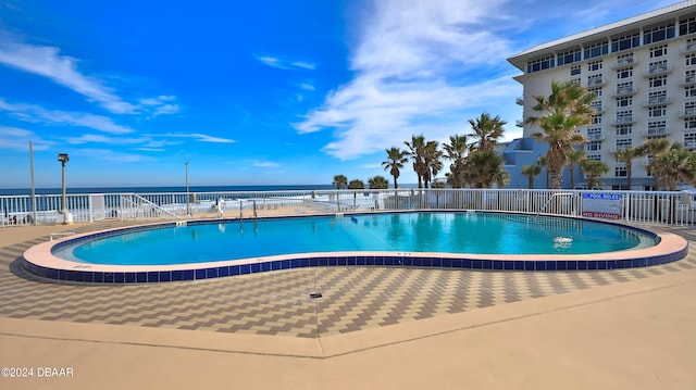 view of swimming pool featuring a water view and a patio area