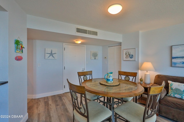 dining room with hardwood / wood-style floors and a textured ceiling