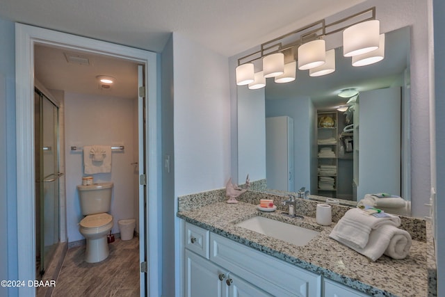 bathroom with toilet, vanity, hardwood / wood-style floors, and walk in shower