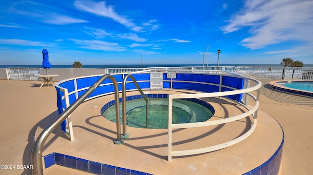 view of pool featuring a hot tub and a water view