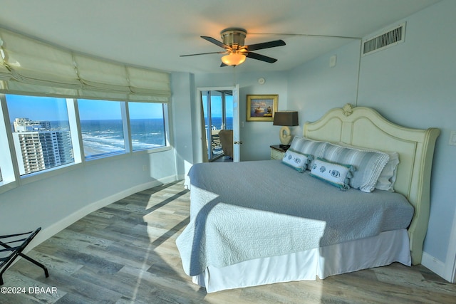 bedroom featuring hardwood / wood-style flooring, ceiling fan, and a water view