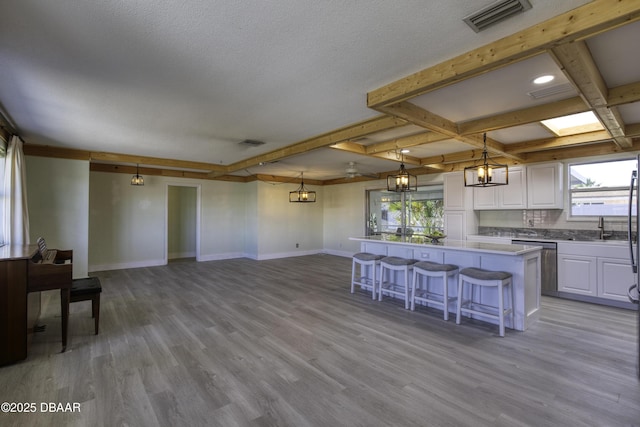 kitchen featuring white cabinetry, a center island, light hardwood / wood-style flooring, and hanging light fixtures