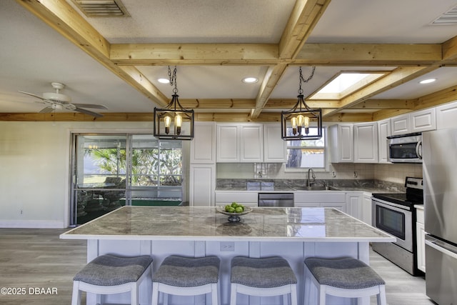 kitchen featuring decorative backsplash, white cabinets, appliances with stainless steel finishes, and a center island