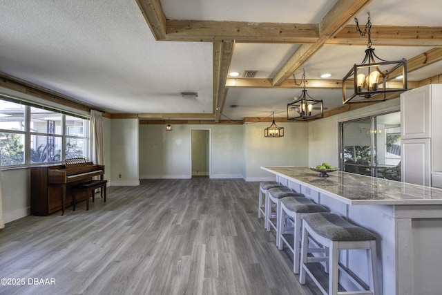 kitchen with hardwood / wood-style flooring, light stone countertops, hanging light fixtures, and white cabinets