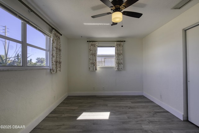 empty room with ceiling fan and dark hardwood / wood-style flooring