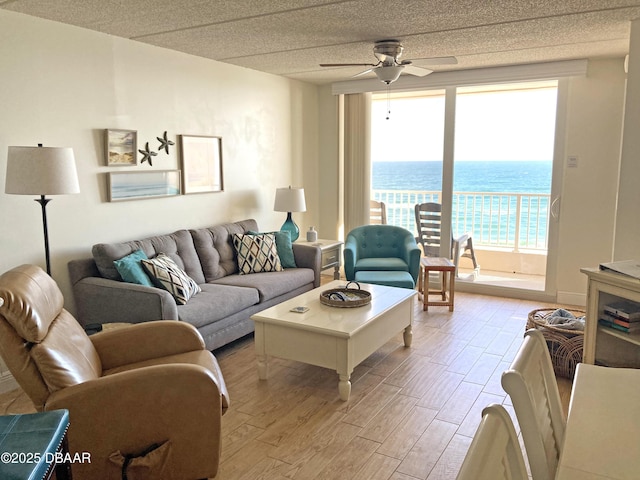 living area featuring a water view, light wood-style flooring, and a ceiling fan