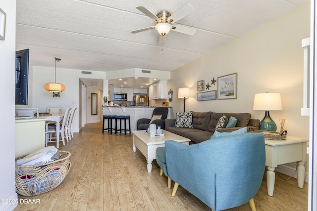 4453 S Atlantic Ave Unit 502, Port Orange, FL 32127 - living room featuring visible vents, a ceiling fan, light wood finished floors, and a textured ceiling