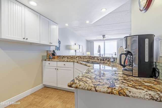 4453 S Atlantic Ave Unit 502, Port Orange, FL 32127 - kitchen featuring ceiling fan, light stone countertops, a sink, white cabinets, and light wood-style floors