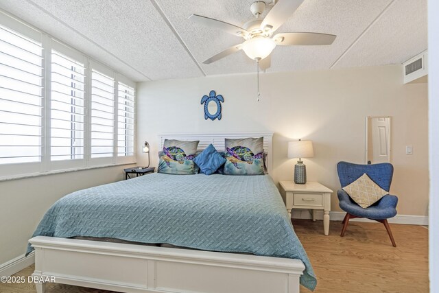 4453 S Atlantic Ave Unit 502, Port Orange, FL 32127 - bedroom featuring a ceiling fan, a textured ceiling, visible vents, wood finished floors, and baseboards