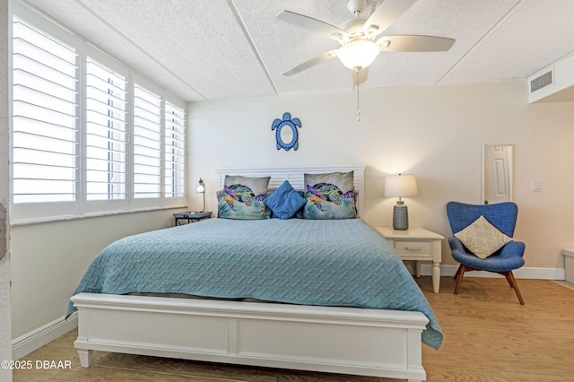 4453 S Atlantic Ave Unit 502, Port Orange, FL 32127 - bedroom featuring ceiling fan, a textured ceiling, visible vents, baseboards, and light wood-style flooring