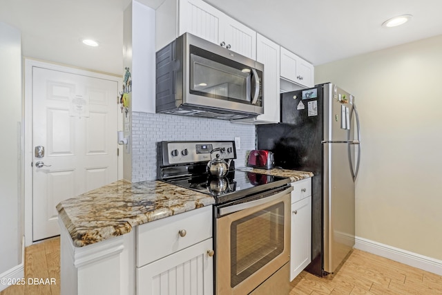 4453 S Atlantic Ave Unit 502, Port Orange, FL 32127 - kitchen featuring backsplash, baseboards, white cabinets, light wood finished floors, and stainless steel appliances