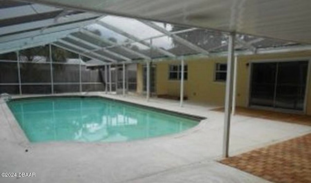 view of swimming pool with glass enclosure and a patio area