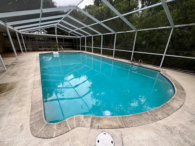 view of pool featuring glass enclosure and a patio area