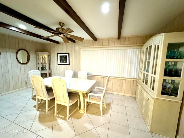 dining room with beam ceiling, wood walls, light tile patterned flooring, and ceiling fan