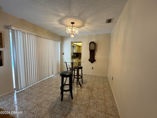 unfurnished dining area with light tile patterned floors, a textured ceiling, and a notable chandelier