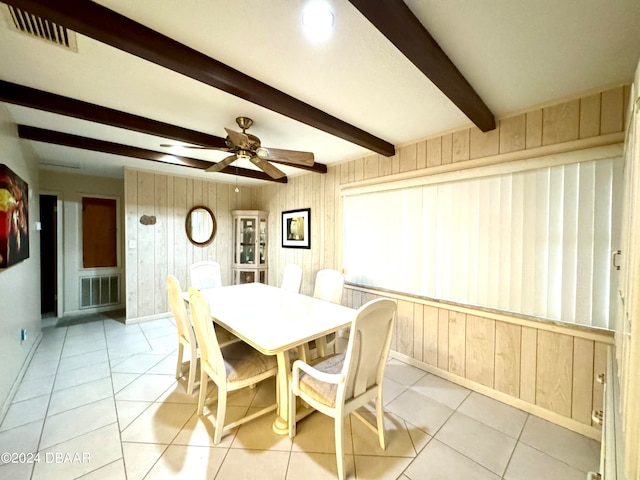 dining room with beamed ceiling, wood walls, and light tile patterned floors