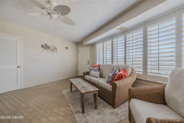 living room with ceiling fan, a textured ceiling, and a wealth of natural light