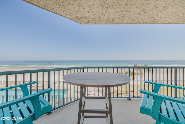 balcony with a water view and a view of the beach