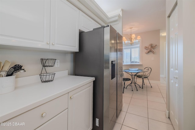 kitchen with white cabinetry, a chandelier, hanging light fixtures, light tile patterned floors, and stainless steel fridge