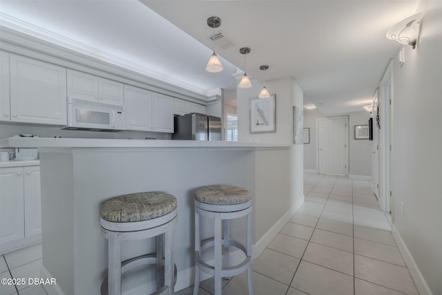 kitchen with a kitchen bar, stainless steel refrigerator, kitchen peninsula, pendant lighting, and white cabinets