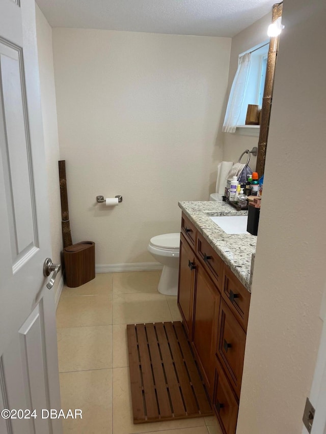 bathroom with toilet, vanity, and tile patterned flooring