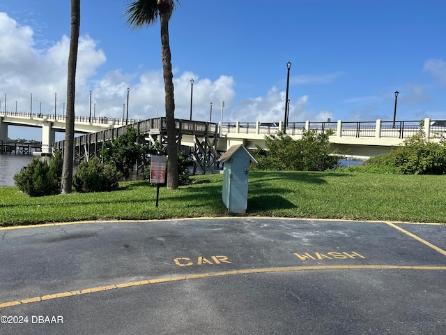 view of vehicle parking featuring a lawn and a water view