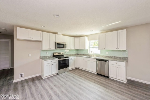495 6th St, Holly Hill, FL 32117 - kitchen featuring stainless steel appliances, decorative backsplash, light wood-style floors, white cabinets, and a textured ceiling