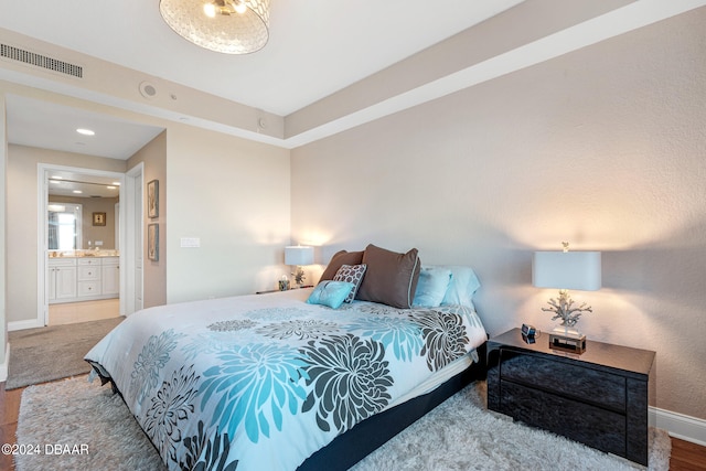 bedroom with hardwood / wood-style flooring and ensuite bathroom