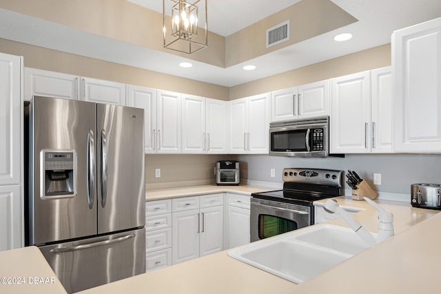 kitchen with an inviting chandelier, hanging light fixtures, sink, white cabinetry, and appliances with stainless steel finishes