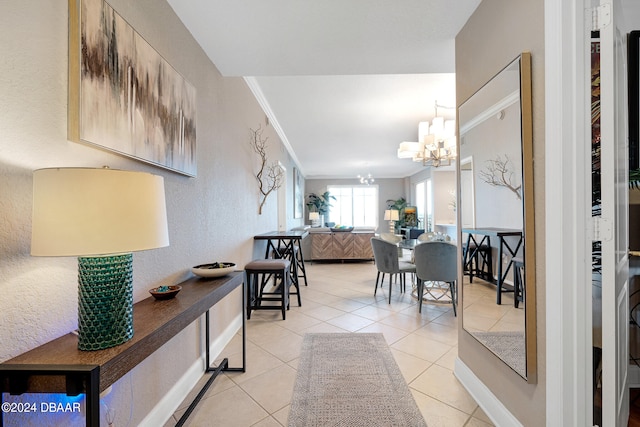 hall featuring a chandelier, crown molding, and light tile patterned flooring