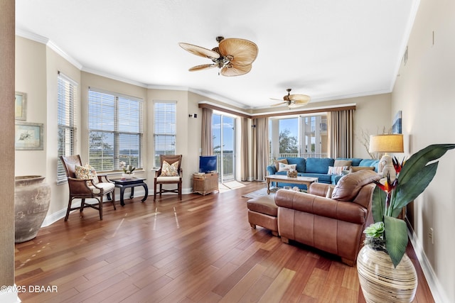 living area featuring crown molding, wood finished floors, a ceiling fan, and baseboards