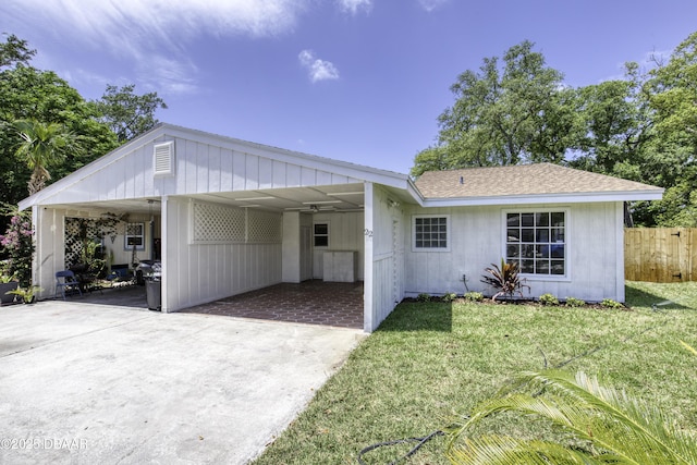 ranch-style house with a front lawn, fence, an attached carport, and concrete driveway