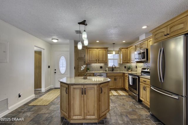 kitchen with a kitchen island, baseboards, stone finish floor, a sink, and stainless steel appliances