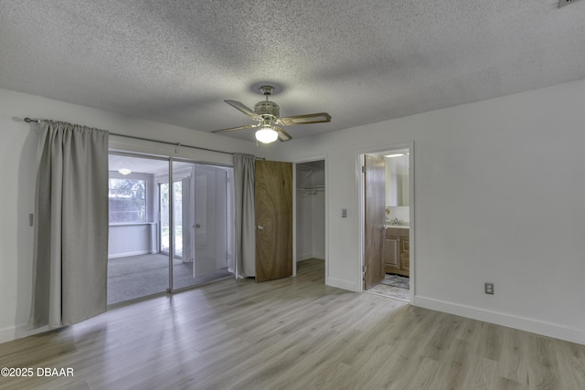 unfurnished bedroom with a textured ceiling, baseboards, light wood-style flooring, and access to exterior