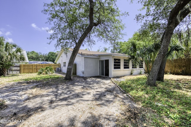 view of front facade with central AC, a fenced backyard, and stucco siding