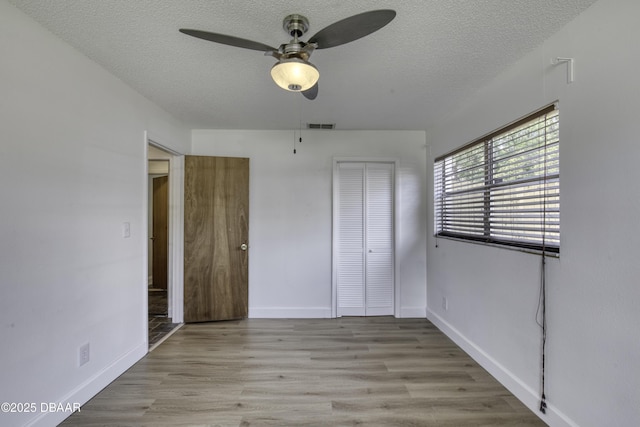 unfurnished bedroom featuring visible vents, a textured ceiling, baseboards, and a closet