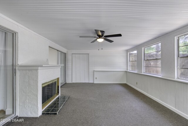 unfurnished living room with ceiling fan, carpet flooring, and a tile fireplace