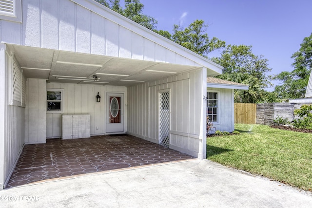 property entrance featuring a yard, a patio, fence, and an attached carport