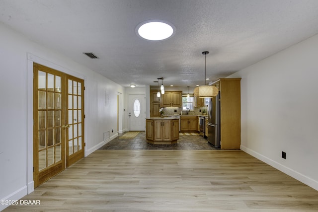 kitchen with freestanding refrigerator, baseboards, a center island, light countertops, and french doors